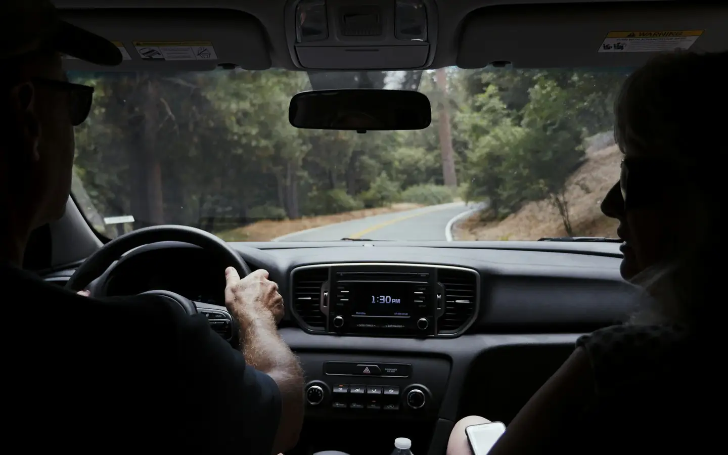 Un conductor con ambas manos en el volante en una carretera soleada