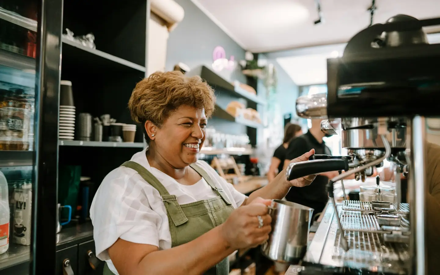 La dueña de un café preparando café detrás del mostrador