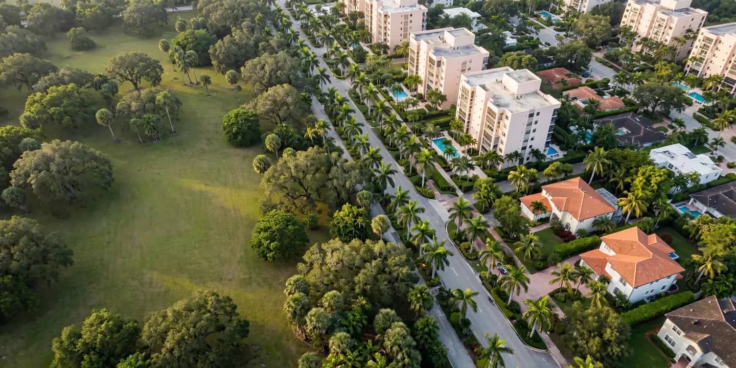 Vista aérea de un bulevar con palmeras, edificios de condominios, casas y un parque