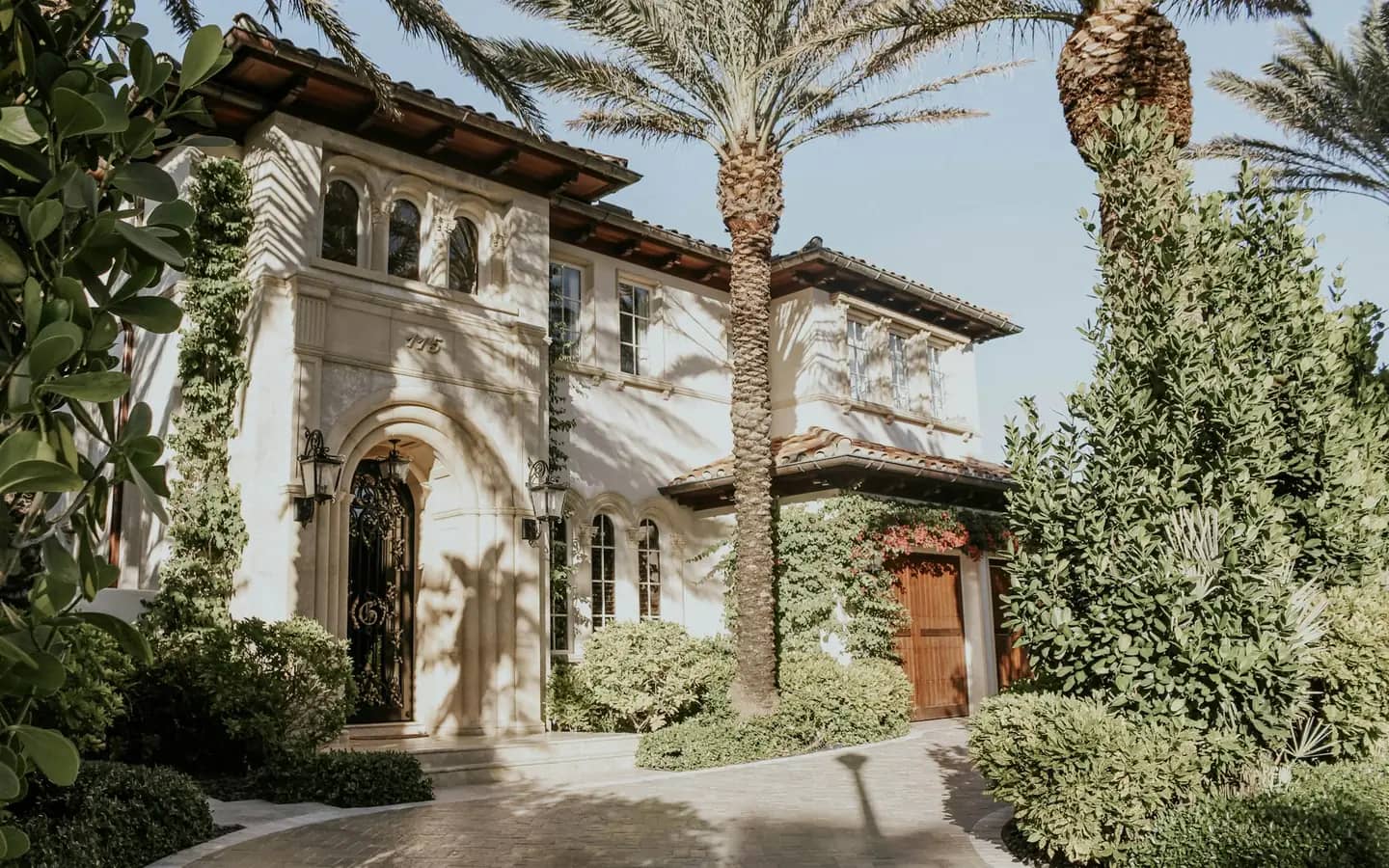 A Mediterranean-style home surrounded by palms and tropical plants