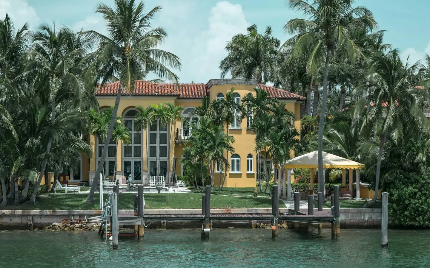 Una casa frente al agua con muelle privado y palmeras